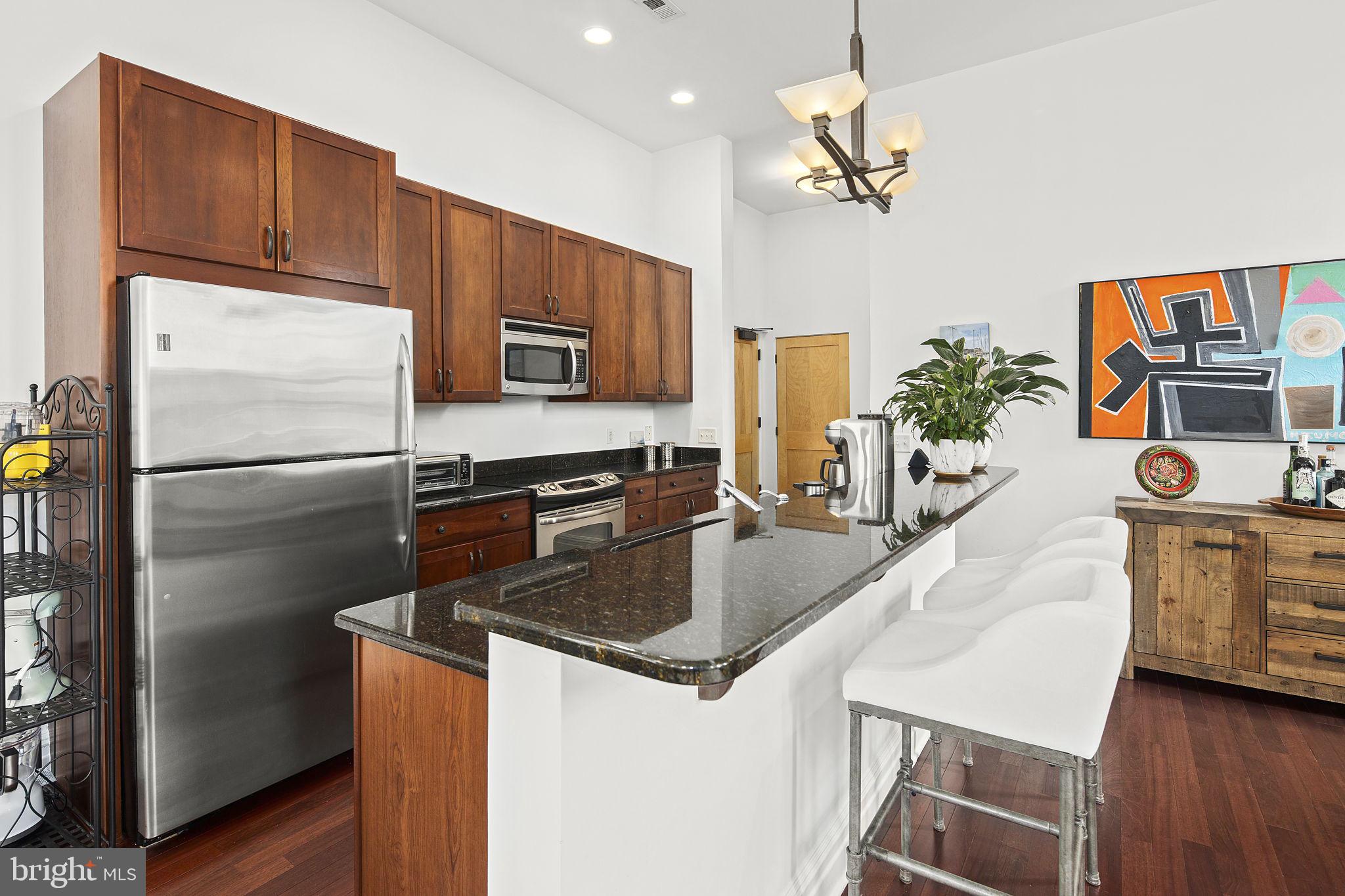 9610 Dewitt Drive, Unit PH204 Silver Spring, MD 20910 - Photo 22 of 42 a kitchen with stainless steel appliances granite countertop a refrigerator a stove a sink dishwasher and a refrigerator with wooden floor