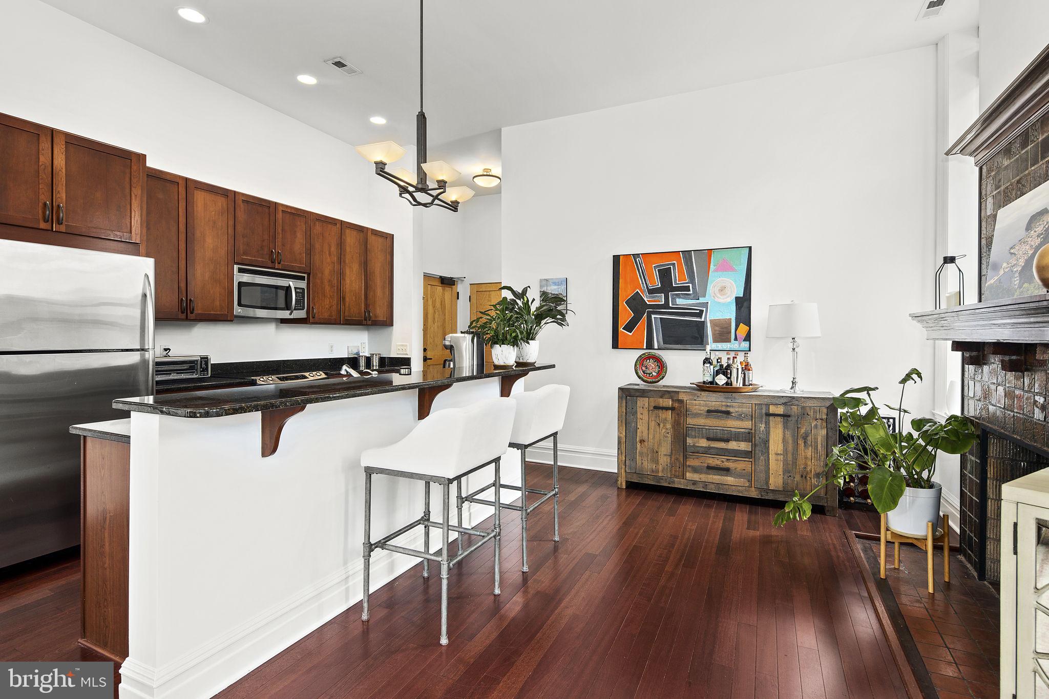 9610 Dewitt Drive, Unit PH204 Silver Spring, MD 20910 - Photo 4 of 42 a kitchen with stainless steel appliances kitchen island granite countertop a stove top oven a sink dishwasher a dining table and chairs with wooden floor