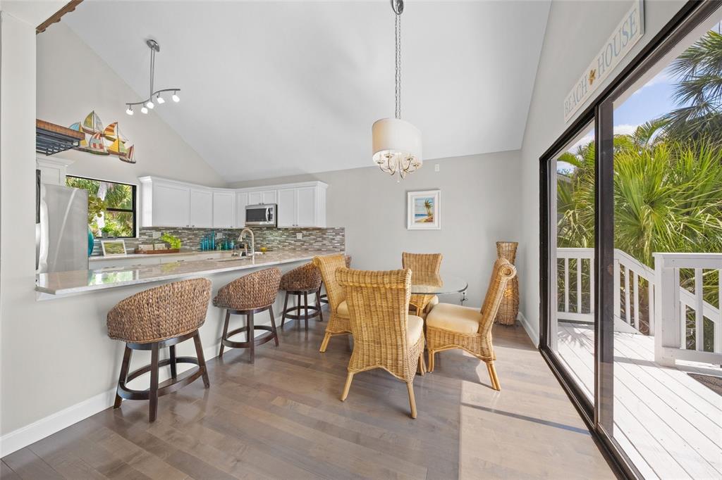 1256 Riegels Landing Drive Sarasota, FL 34242 - Photo 4 of 40 a dining room with wooden floor a chandelier a glass table and chairs