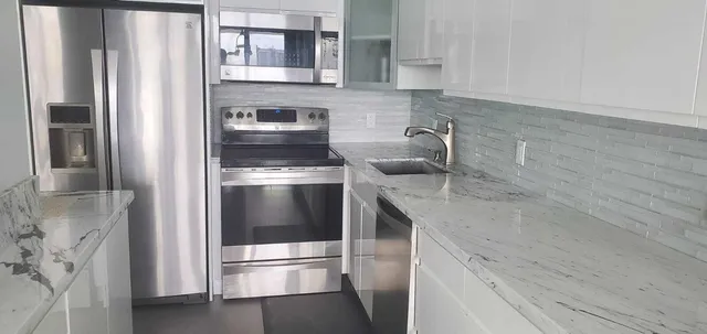 a kitchen with stainless steel appliances granite countertop a refrigerator and a sink