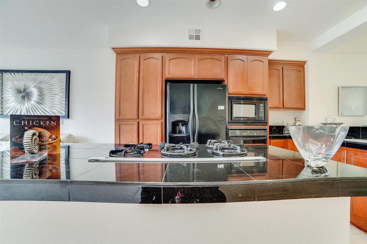 49030 Meadowfaire Common Fremont, CA 94539 - Photo 14 of 52 a kitchen with kitchen island granite countertop a sink and a stove with wooden floor