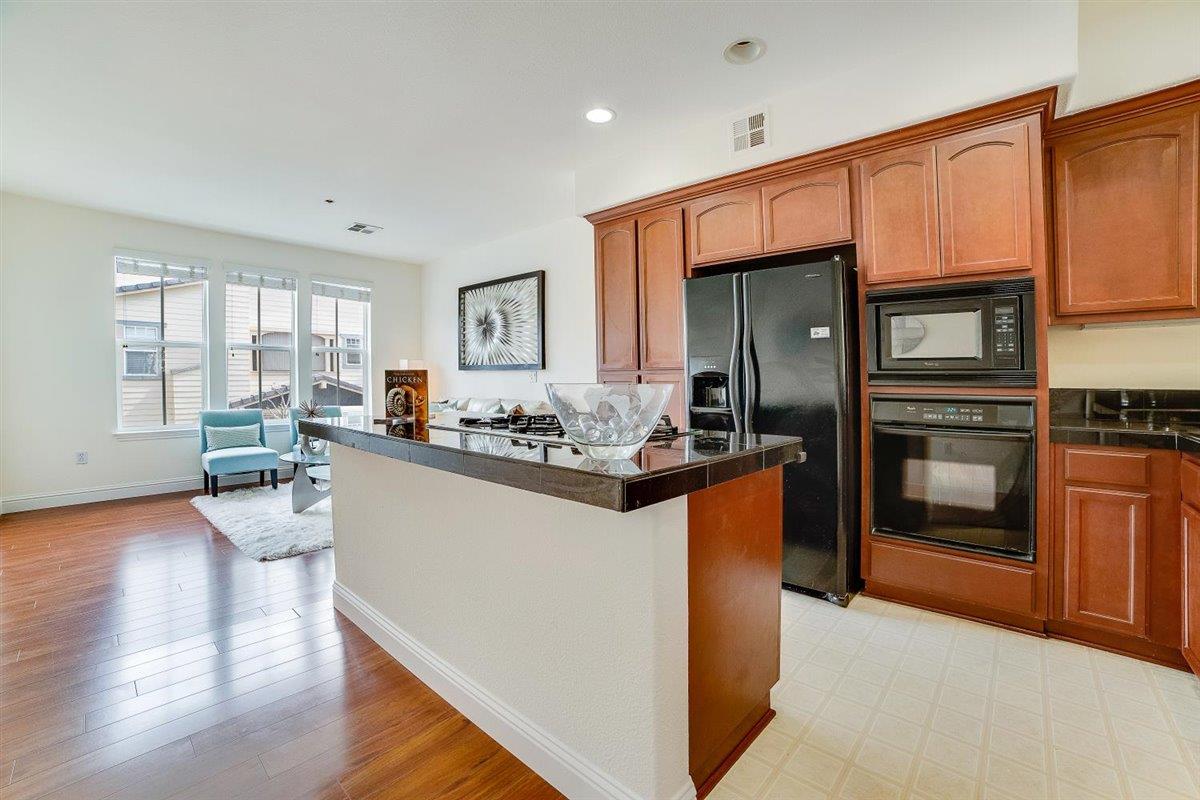 49030 Meadowfaire Common Fremont, CA 94539 - Photo 5 of 52 a kitchen with stainless steel appliances granite countertop a refrigerator a stove and a wooden floors