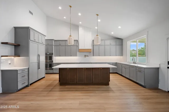a kitchen with stainless steel appliances granite countertop a stove a sink a refrigerator and a oven with wooden floor