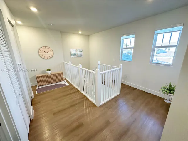 a view of a hallway to a livingroom with wooden floor and stairs