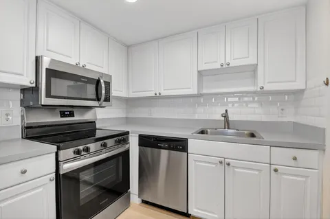 a kitchen with cabinets stainless steel appliances a sink and a counter space