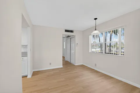a view of an empty room with chandelier fan and fire place