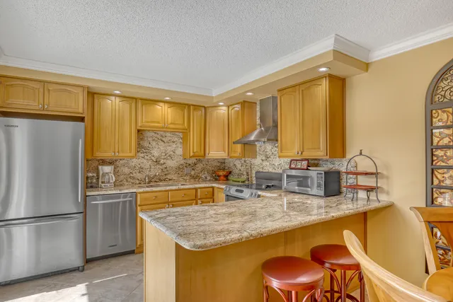 a kitchen with stainless steel appliances granite countertop a sink and a refrigerator