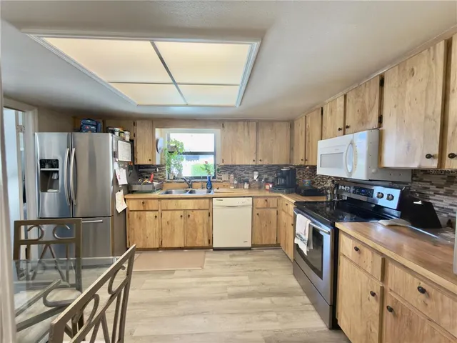 a kitchen with a sink stainless steel appliances wooden floor and a window