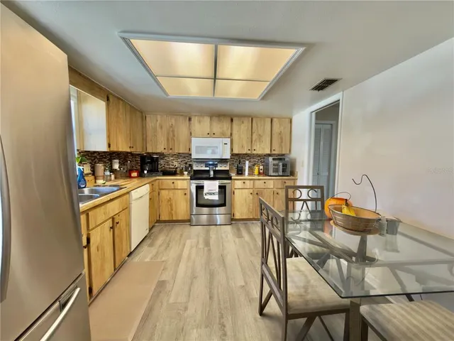 a kitchen with stainless steel appliances kitchen island granite countertop a stove a sink a dining table and chairs with wooden floor