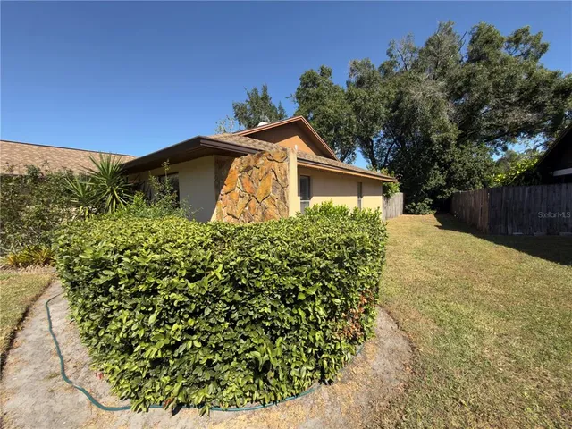 a front view of a house with a yard and covered with trees