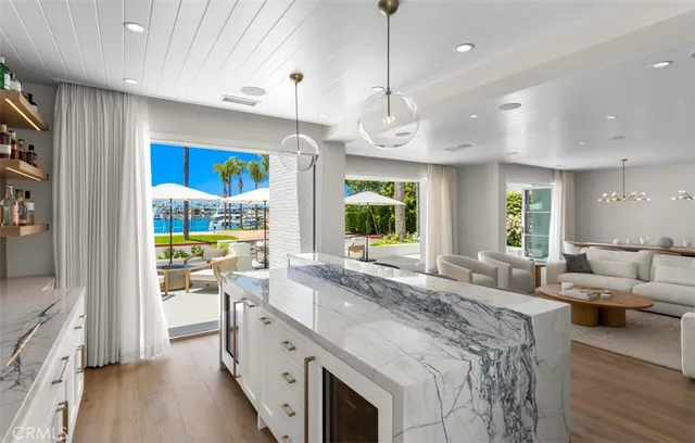 a large white kitchen with a large island oven a stove white cabinetry and couches with wooden floor