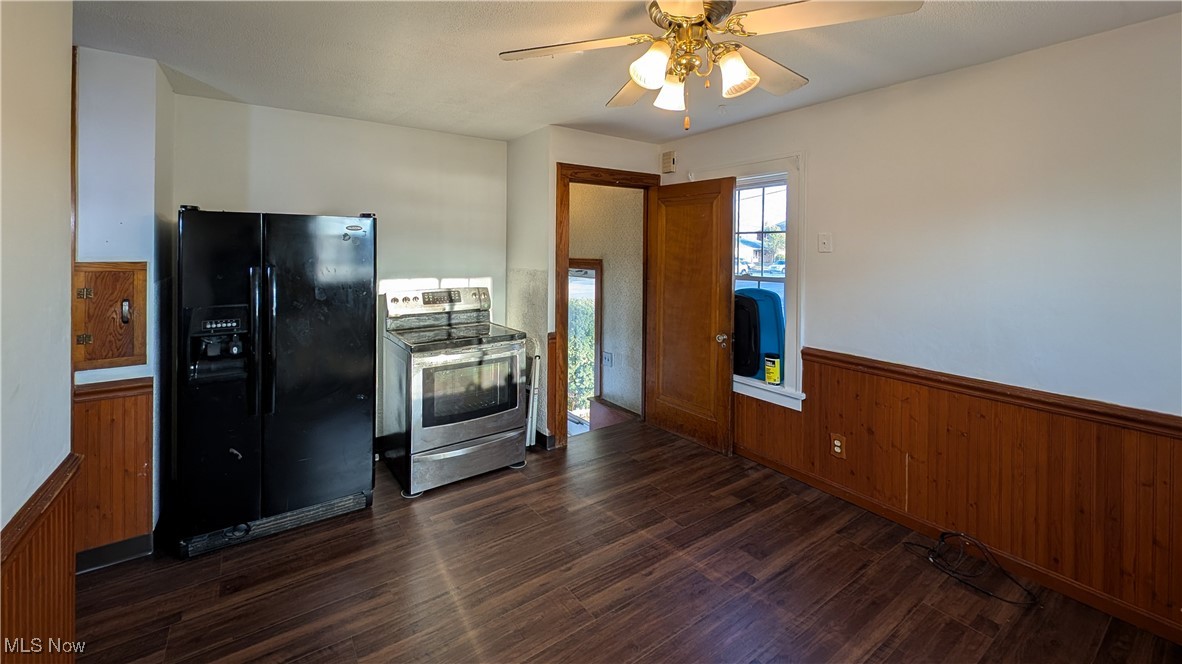 2511 Milan Road Sandusky, OH 44870 - Photo 12 of 40 Kitchen featuring wooden walls, black refrigerator with ice dispenser, dark wood-type flooring, and stainless steel electric range
