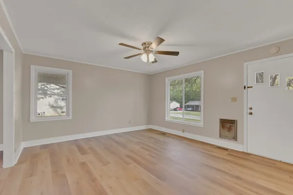 a view of empty room with wooden floor and fan
