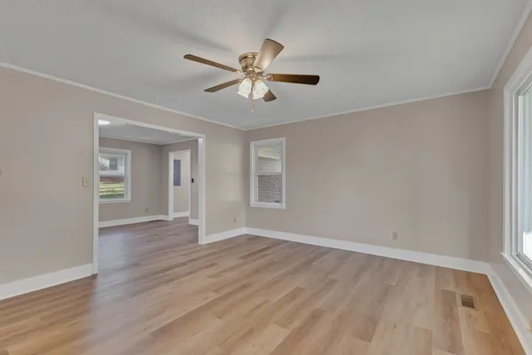 a view of an empty room with wooden floor and a window