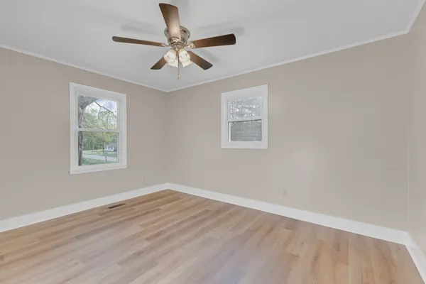 a view of a big room with wooden floor and windows