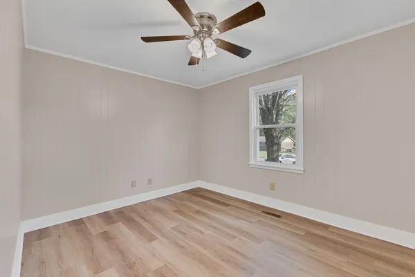an empty room with a window and a fan