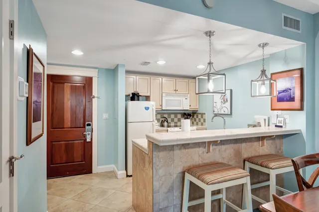 a kitchen with stainless steel appliances kitchen island granite countertop a refrigerator a sink a stove a dining table and chairs