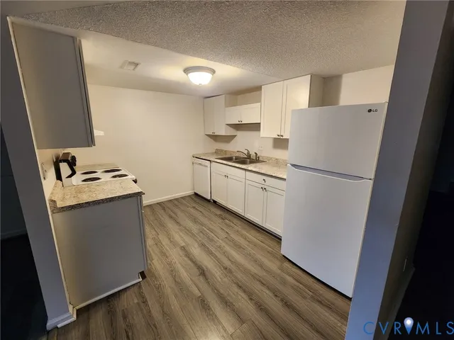 a kitchen with sink a refrigerator and wooden floor