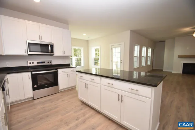 a kitchen with granite countertop white cabinets and stainless steel appliances