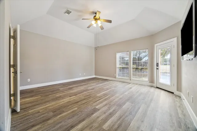 a view of an empty room with a window and wooden floor