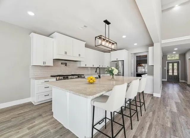 a kitchen with stainless steel appliances kitchen island granite countertop a wooden floor and white cabinets