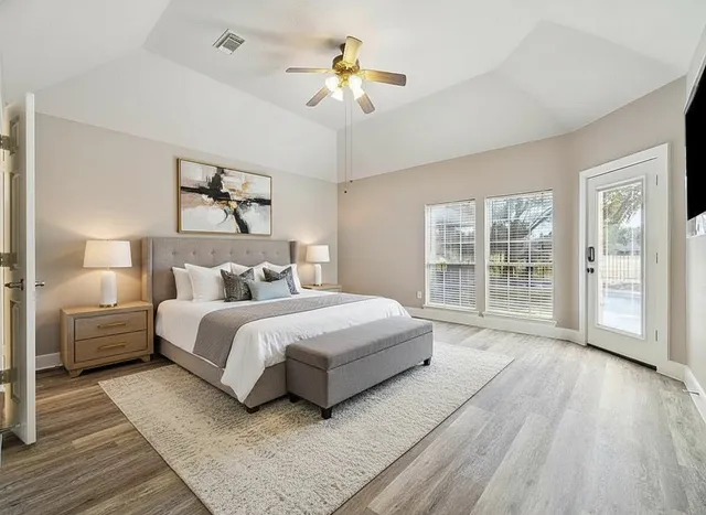 a spacious bedroom with a large bed a chandelier and windows