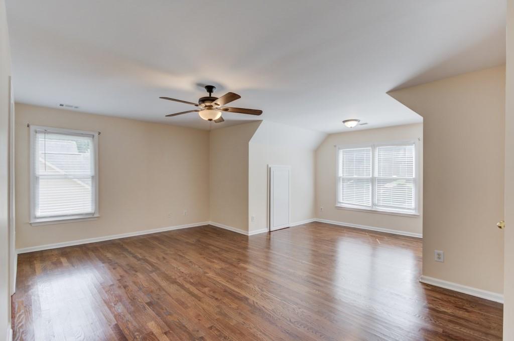 2405 Millwater Crossing Northeast Dacula, GA 30019 - Photo 40 of 63 an empty room with wooden floor chandelier fan and windows
