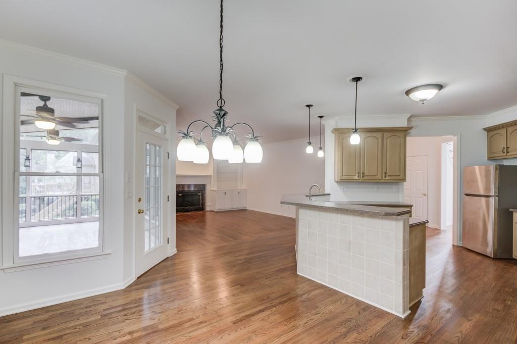 2405 Millwater Crossing Northeast Dacula, GA 30019 - Photo 49 of 63 a open kitchen with a refrigerator a sink dishwasher and a fireplace with wooden floor