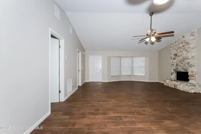 a view of an empty room with chandelier fan and a window