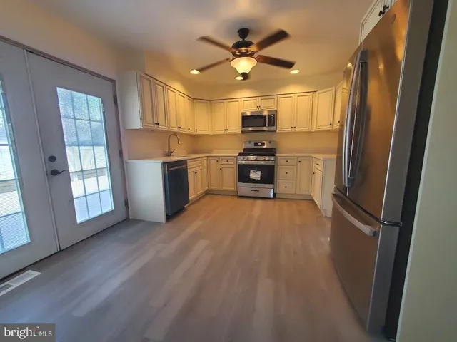 a open kitchen with stainless steel appliances wooden floor and a refrigerator