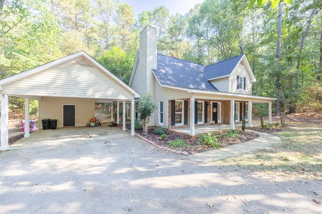 a view of a house with a yard plants and large tree
