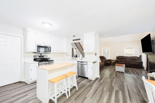 a kitchen with stainless steel appliances a stove top oven a sink dishwasher and a refrigerator with wooden floor