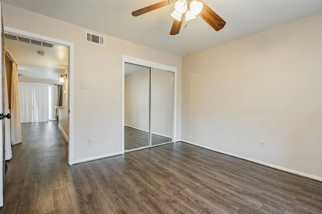 an empty room with wooden floor chandelier fan and closet area