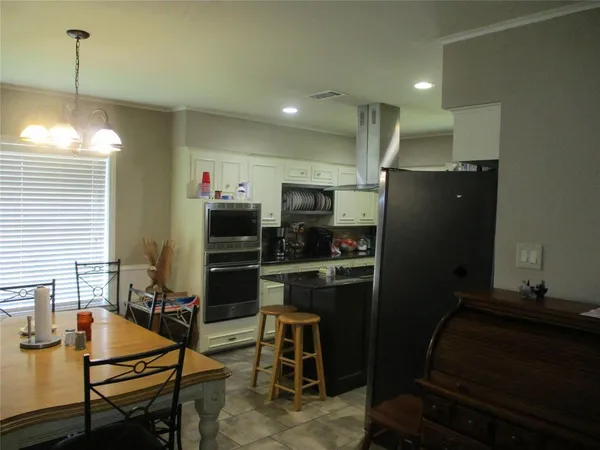 a kitchen with stainless steel appliances granite countertop a stove a sink a microwave a refrigerator and white cabinets