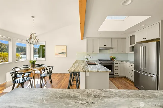 a kitchen with granite countertop a refrigerator a stove a sink a dining table and chairs with wooden floor