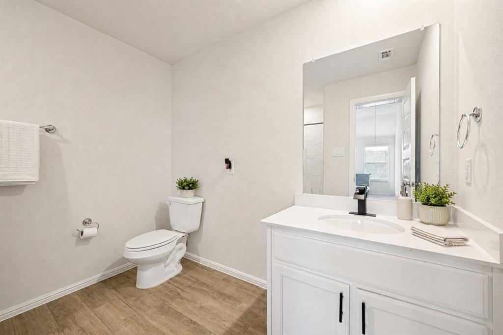 14065 Ilderton Street Pilot Point, TX 76258 - Photo 14 of 19 14065 Ilsderton St., Pilot Point Tx Bathroom featuring wood-finish flooring, a white vanity with an integrated sink, a large wall-mounted mirror, and a modern matte black faucet