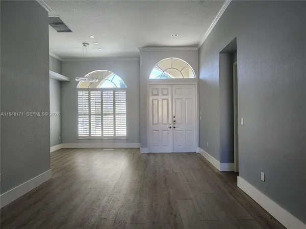 an empty room with wooden floor and windows