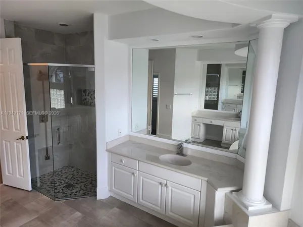a bathroom with a granite countertop sink a mirror and shower