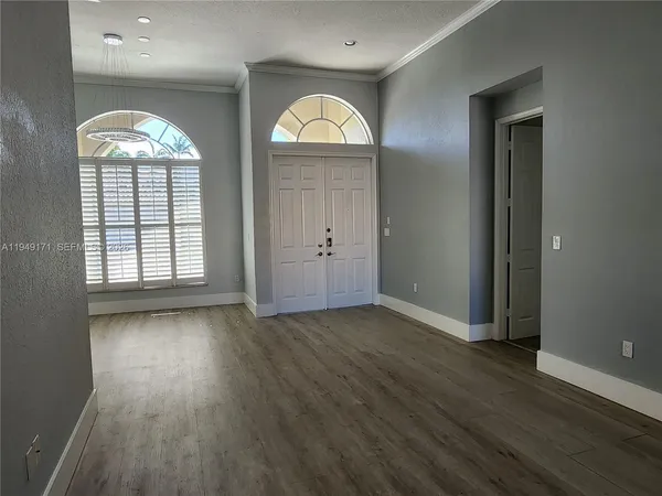 an empty room with wooden floor mirror and window