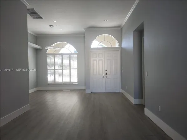an empty room with wooden floor and windows