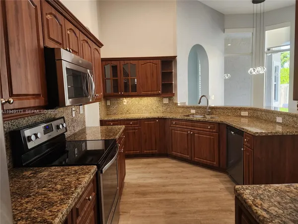 a kitchen with stainless steel appliances granite countertop a stove a sink and a microwave