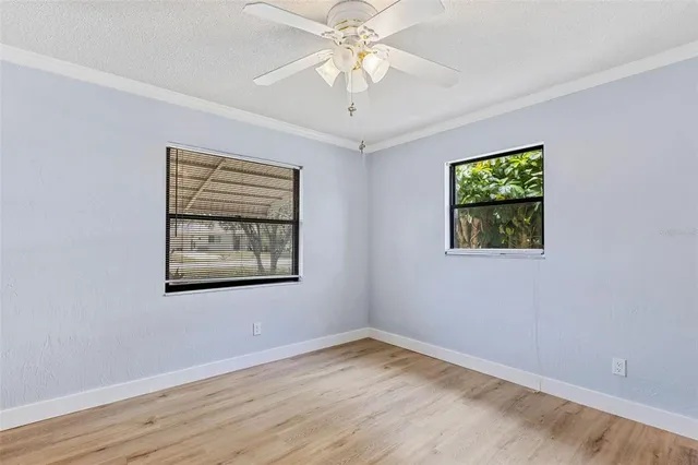 a view of empty room with wooden floor and ceiling fan