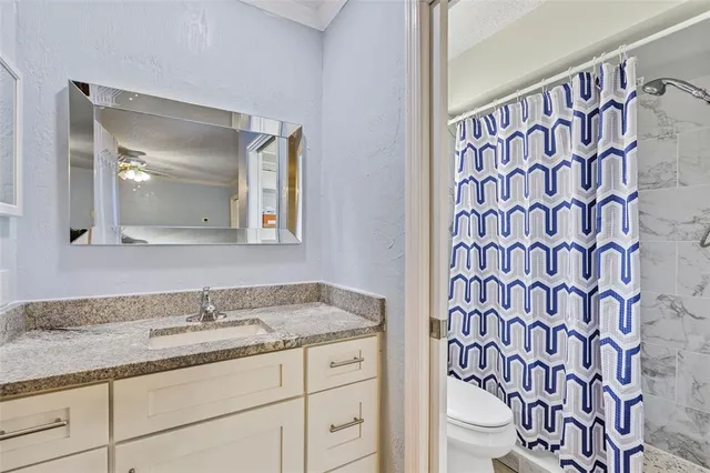 a bathroom with a granite countertop sink a toilet and a mirror