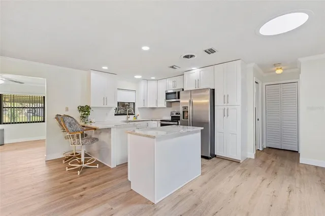 a kitchen with kitchen island white cabinets and stainless steel appliances