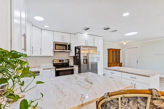 a kitchen with stainless steel appliances kitchen island granite countertop a stove a sink dishwasher and a microwave with wooden floor