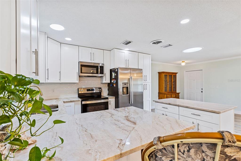 1855 Pine Tree Drive Edgewater, FL 32141 - Photo 8 of 26 a kitchen with stainless steel appliances kitchen island granite countertop a stove a sink dishwasher and a microwave with wooden floor