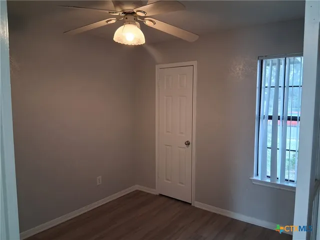a view of an empty room with wooden floor and windows