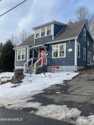 a front view of a house with a yard covered with snow