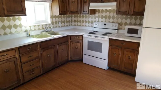 a view of kitchen with stainless steel appliances granite countertop cabinets and window