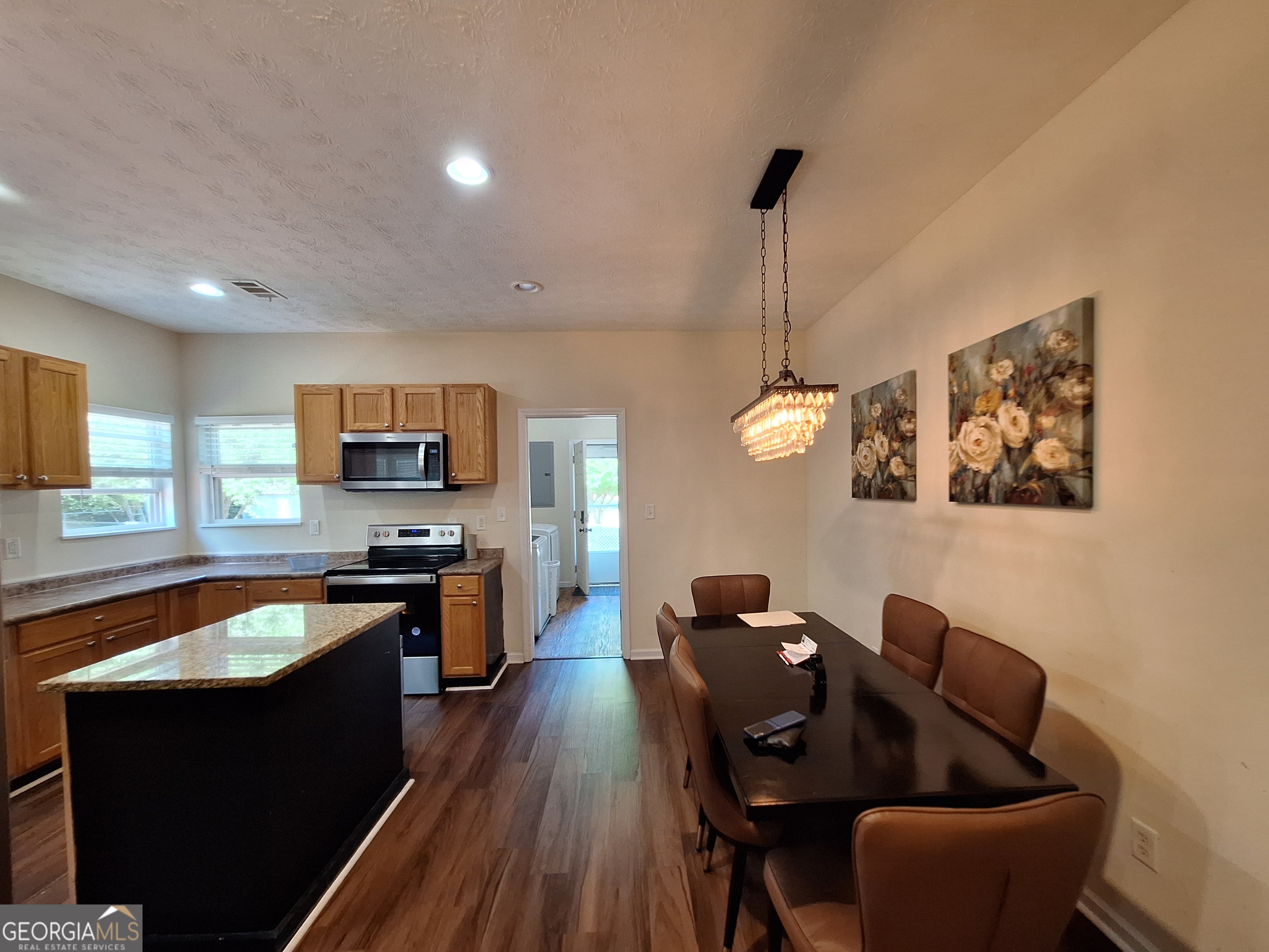 806 Springfield Drive Lafayette, AL 36862 - Photo 9 of 19 a open kitchen with stainless steel appliances granite countertop a stove a sink a microwave a dining table and chairs with wooden floor